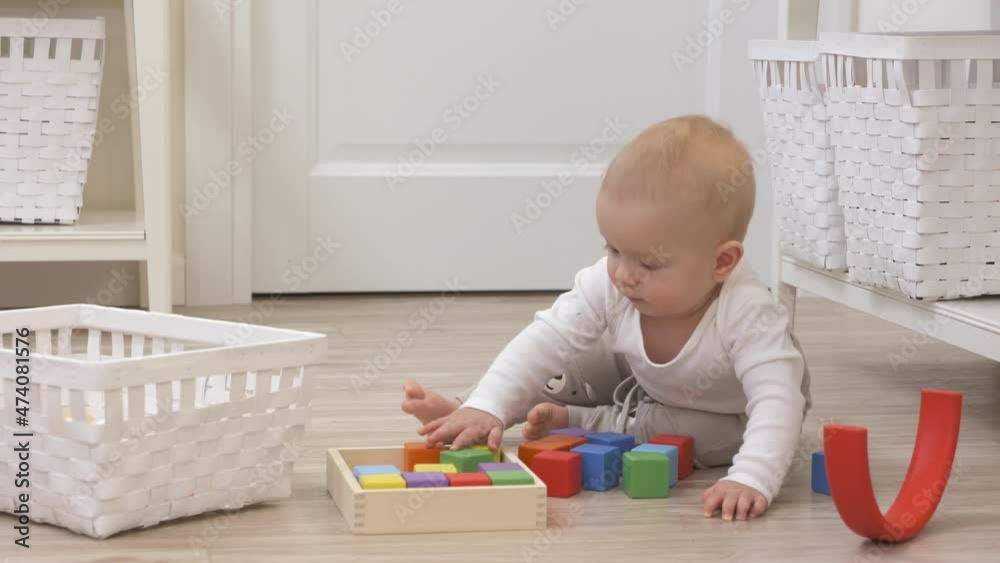 Baby boy sitting on the floor playing with colorful wooden building blocks and rainbow stacker, 9 month old kid picks up cubes at home. High quality 4k footage Baby boy sitting on the floor playing with colorful wooden building blocks and rainbow stacker, 9 month old kid picks up cubes at home. High quality 4k footage
