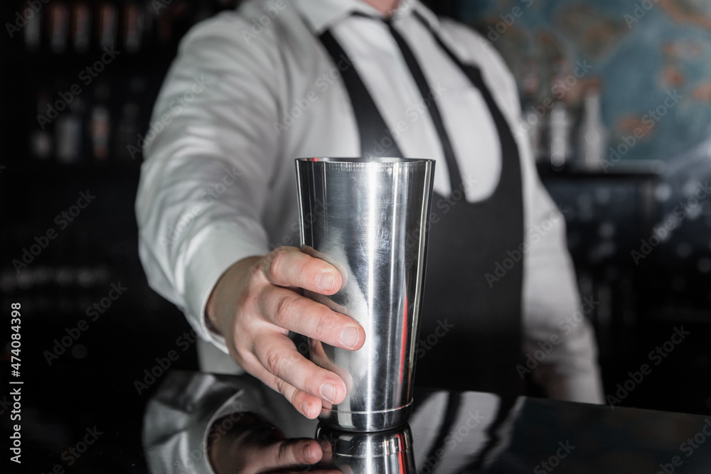 The hand of a professional bartender takes a tool for cooking and mixing alcoholic cocktail shaker, close-up