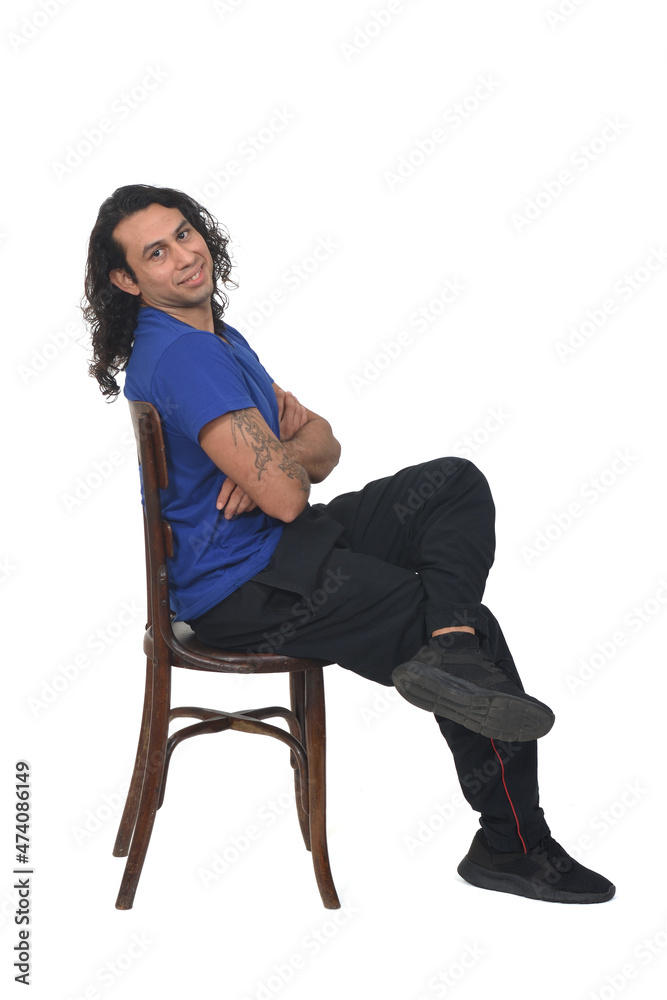 side view of a man with sportswear sitting on chair looking at camera legs and arms crossed on white background side view of a man with sportswear sitting on chair looking at camera legs and arms crossed on white background