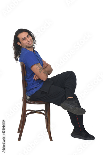 side view of a man with sportswear sitting on chair looking at camera legs and arms crossed on white background