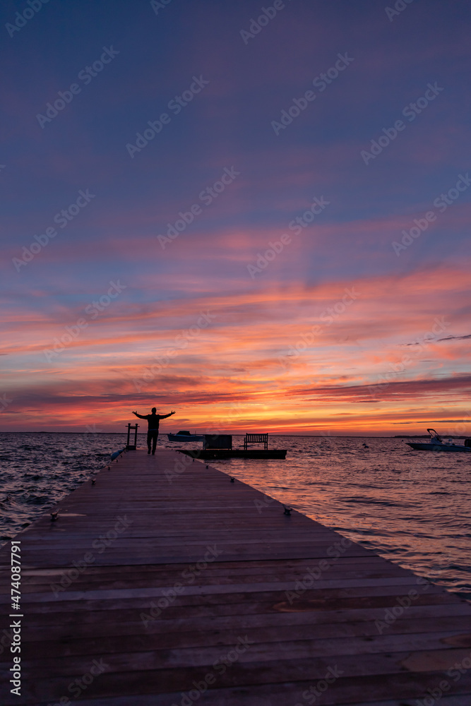 Silhouette of man raising his arms beneath incredible sunset sky.