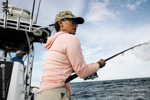 A woman hold fishing rod and looks out to the water on fishing boat photo