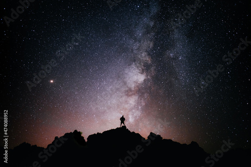 A person standing looking at the star field and the milky way photo