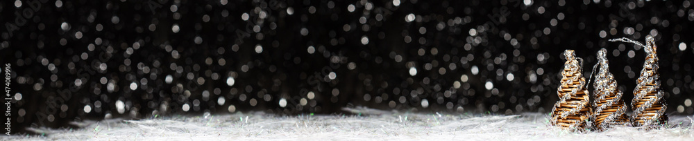 Christmas banner decorations view of three wooden tree colored in solver glitter at the tips and white hedgehog on dark background with silver colors bokeh and artificial snow. Holidays concept Christmas banner decorations view of three wooden tree colored in solver glitter at the tips and white hedgehog on dark background with silver colors bokeh and artificial snow. Holidays concept