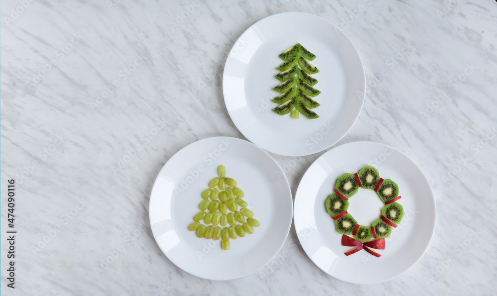 Funny edible Christmas tree an wreath, breakfast or snack idea for kids. Made of kiwi and grape. New Year, foodie, food concept. White marble granite background. top view, flat lay, space for text Funny edible Christmas tree an wreath, breakfast or snack idea for kids. Made of kiwi and grape. New Year, foodie, food concept. White marble granite background. top view, flat lay, space for text