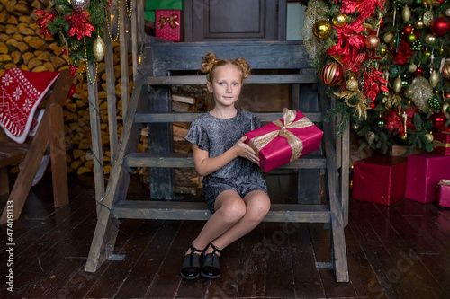 Little beautiful girl with a red Christmas gift. The girl laughs. Happy joyful girl. Christmas decoration.