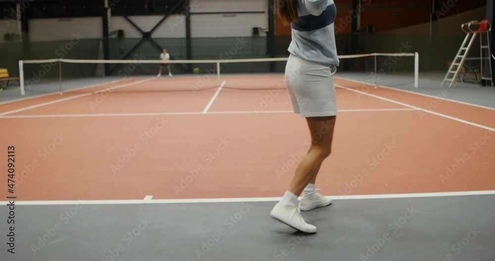 Young athletes play tennis in a large hall alone, throwing the ball with racket Young athletes play tennis in a large hall alone, throwing the ball with racket