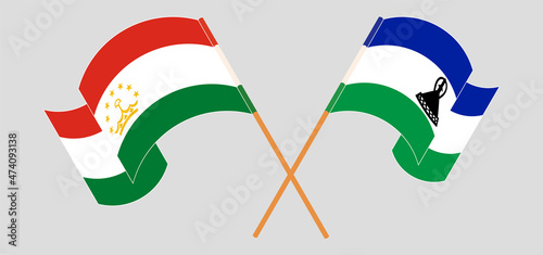 Crossed and waving flags of Tajikistan and Kingdom of Lesotho