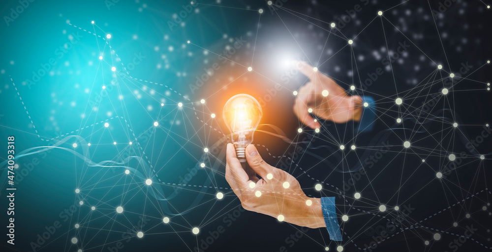 Fototapeta premium The Man hand holding light bulb with line connect and working on the desk, Creativity and innovation are keys to success.Concept of new idea and innovation with energy and power , working at home,