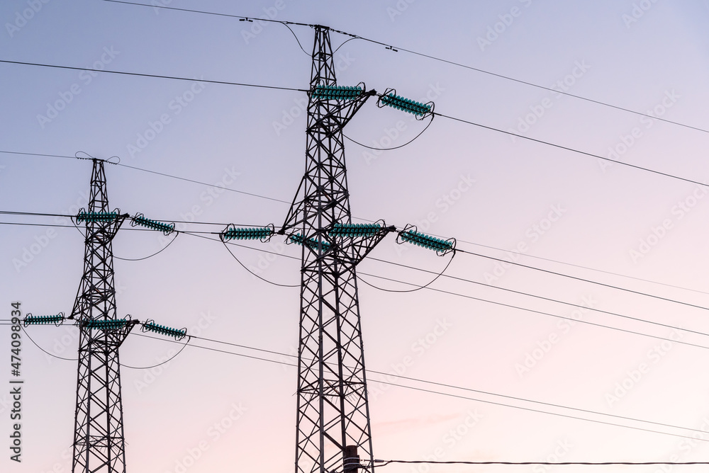 View of two electricity pylons against clear sky at dusk in winter
