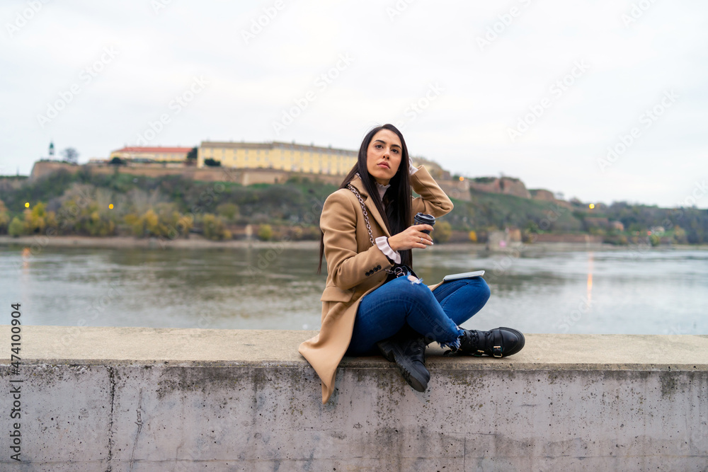 Young beautiful woman using smartphone and drinking coffee takeaway