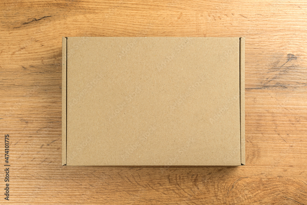 Brown cardboard box on wooden table background. Mockup, concept of delivery and shipping your products and goods etc. Brown cardboard box on wooden table background. Mockup, concept of delivery and shipping your products and goods etc.