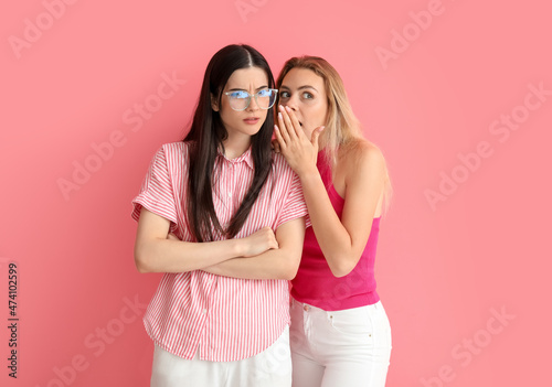 Young gossiping women on color background photo