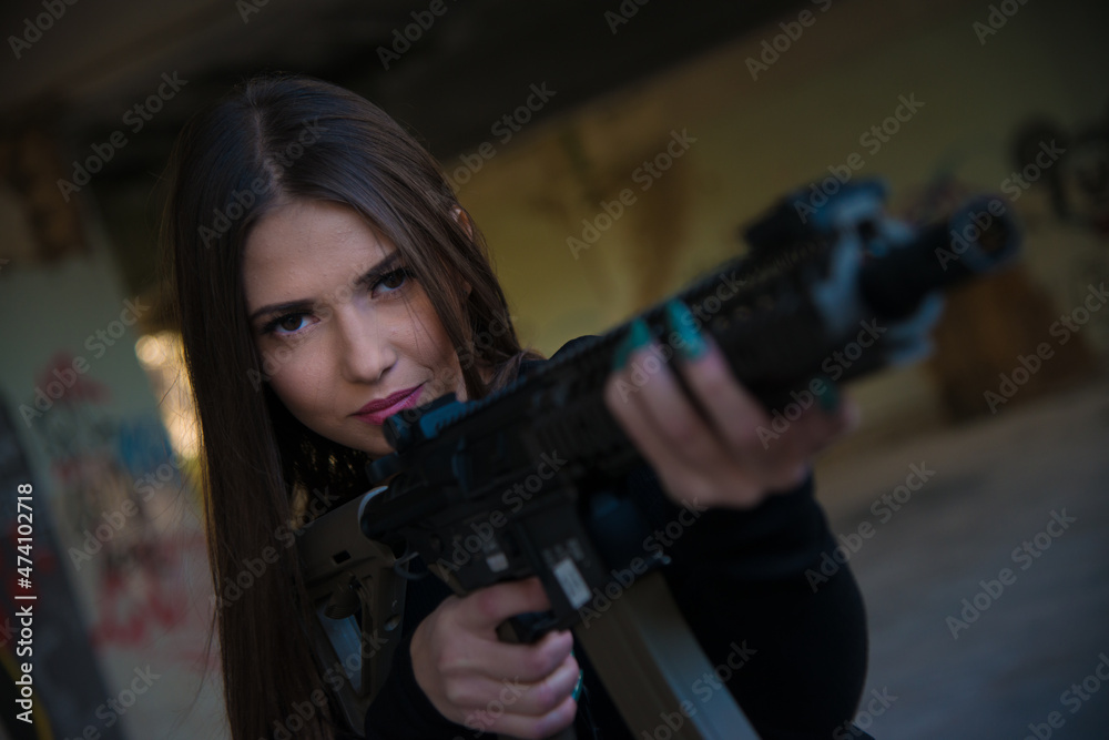 Girl with an air soft rifle in a black tight long-sleeved T-shirt and camouflage cargo pants Girl with an air soft rifle in a black tight long-sleeved T-shirt and camouflage cargo pants