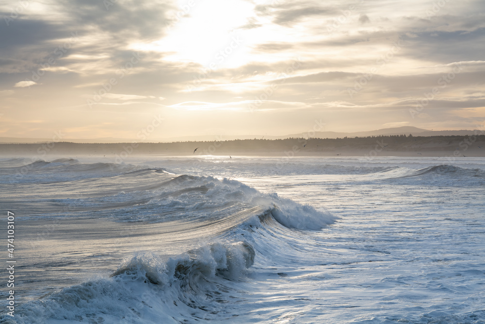 Fototapeta premium LOSSIEMOUTH, MORAY, SCOTLAND - 9 DECEMBER 2021: This is a scene at the east beach area of the harbour with waves just after sunrise at Lossiemouth, Moray, Scotland on 9 December 2021.