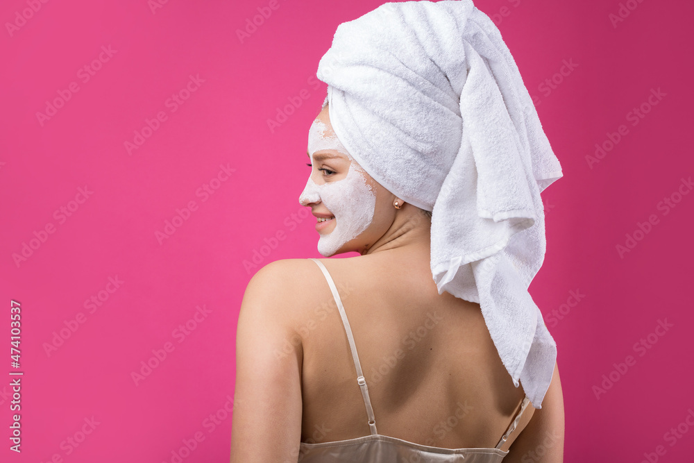 Fototapeta premium Girl with a cosmetic mask on her face in a white towel.