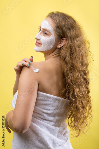 Girl with a cosmetic mask on her face in a white towel.