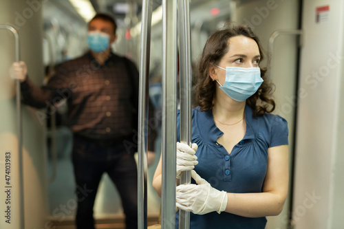 Man and woman in protective medical masks in a subway carriage © JackF