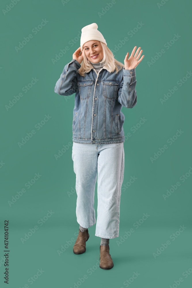Beautiful mature woman in warm clothes on color background