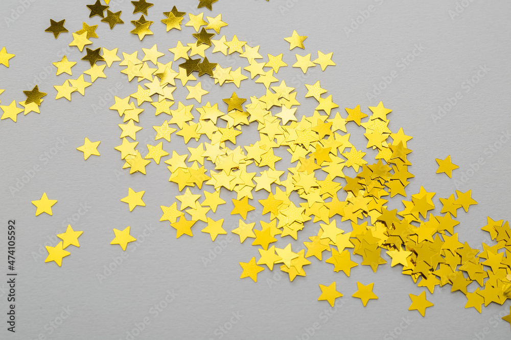 Golden confetti in shape of stars on grey background, closeup Golden confetti in shape of stars on grey background, closeup