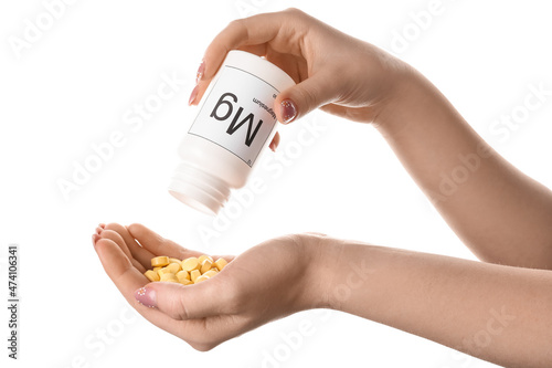 Female hands with bottle of magnesium pills on white background, closeup photo