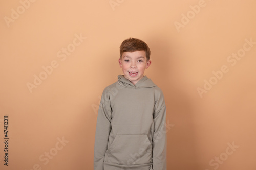 Handsome young european guy teenager looking at camera, wearing casual green hoodie isolated on brown background. copy free space for text.