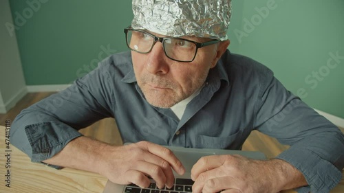 Worried Man in Glasses Works on a Laptop Anxiously Peers Up at. Paranoid Fear, Espionage, Mind Control, Conspiracy Theory, Mind Control. Medical Services Concept, Mental Health. photo