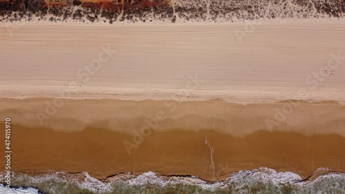 Aerial shot of the coastline next to Rocha Baixinha in the Algarve, sunny morning light. Surf of the sea on the red colored beach. Flying above the Atlantic Ocean upwards. photo