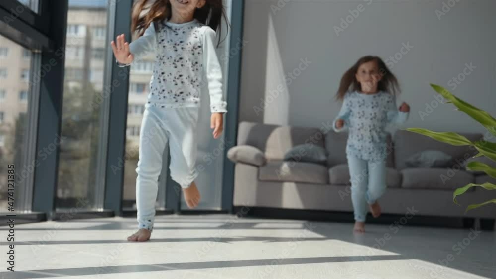 Two cute little girls in nightwear together at daytime in modern room
