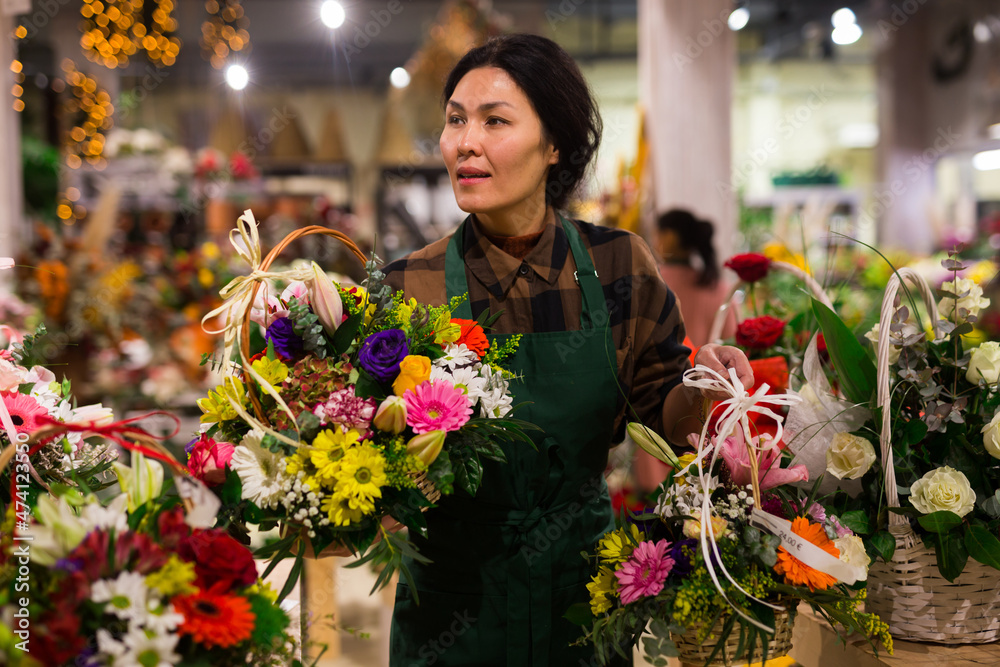 Fototapeta premium Portrait of a confident and successful Asian florist woman standing in a shop with flowers in her hands