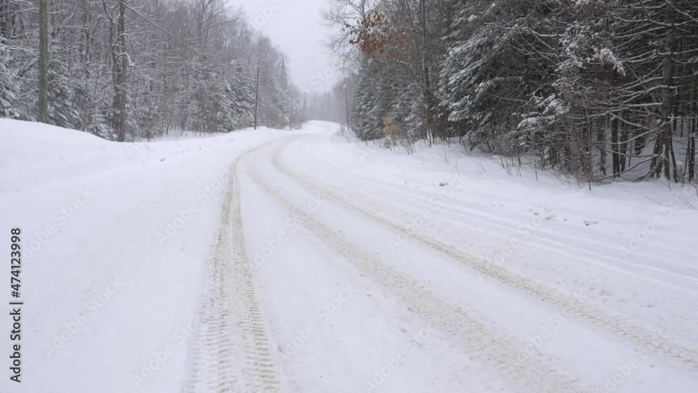 Tire tracks on curvy rural snow-covered winter road. Slow motion snow falling. Haliburton, Ontario, Canada. Tire tracks on curvy rural snow-covered winter road. Slow motion snow falling. Haliburton, Ontario, Canada.