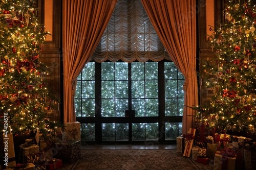 A beautiful room with large glass window  tall curtains and Christmas trees