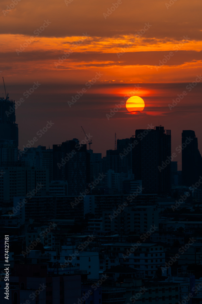 The sun was setting in the evening, a golden orange light shone all around. with a backdrop of tall buildings in a large city in the shadows
