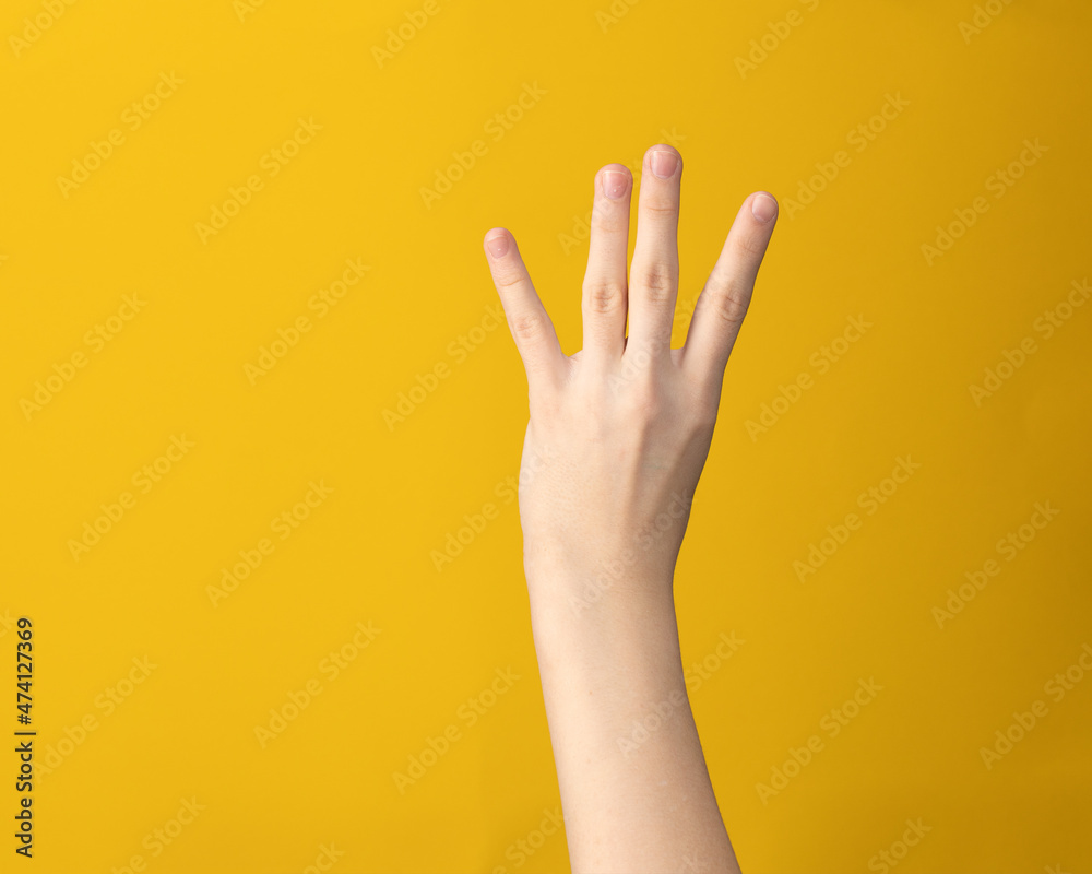 Female hand gesture on yellow background. Woman hand isolated showing index, middle, ring and little four fingers. Female hand gesture on yellow background. Woman hand isolated showing index, middle, ring and little four fingers.