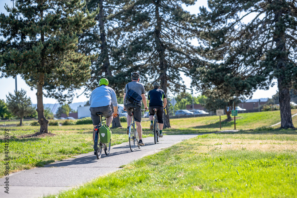 Three cyclists enthusiasts for active healthy lifestyles ride in a column along the bike path