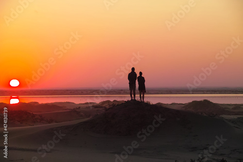 Two people looking at a sunset sunrise in the Namib desert