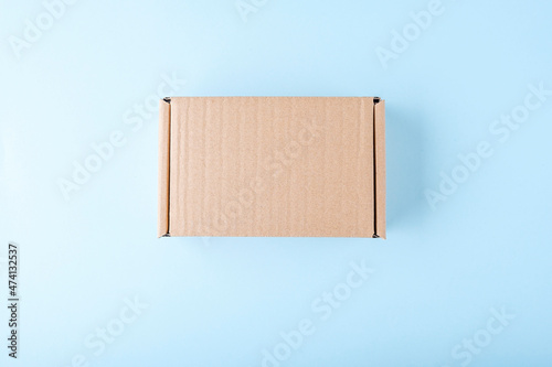 Blank cardboard box package on blue background. Craft paper box for gift. Shipping eco package. Delivery pack, plastic free. Mock uo, copy space for © Elena