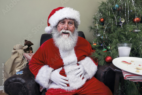 Santa Claus with a stomach ache after eating too many cookies and drinking milk left out on Christmas Eve photo