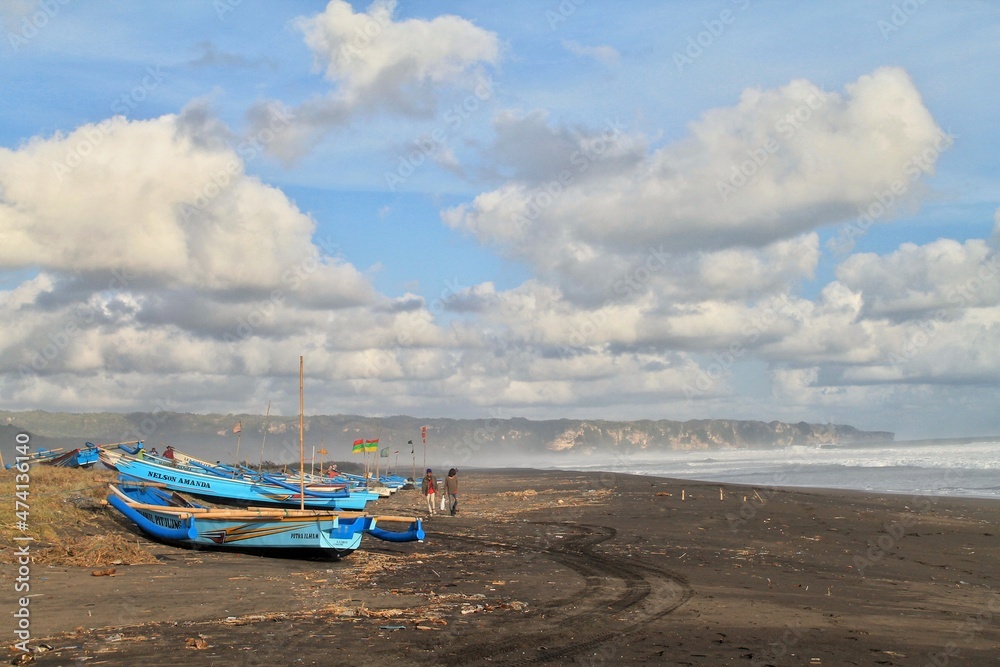 The boat, fisherman, and thick clouds at Depok beach, Yogyakarta, Indonesia.