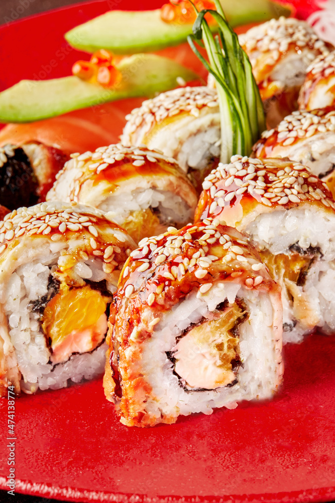 Sushi rolls with eel, cream cheese and orange topped with unagi sauce and sesame