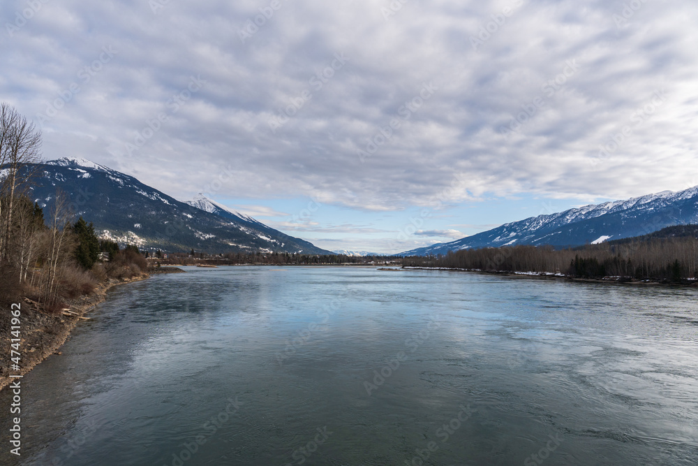 Naklejka premium wide Columbia river with snow in mountains blue sky early spring British Columbia Canada