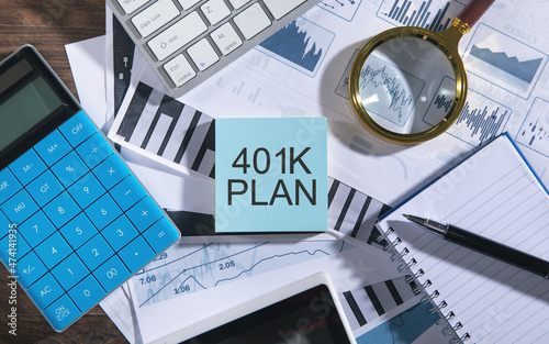 Text 401K Plan with tablet, keyboard, calculator, notepad and financial graphs. photo
