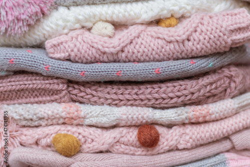 A stack of knitted baby hats and snoods in beige and pink shades