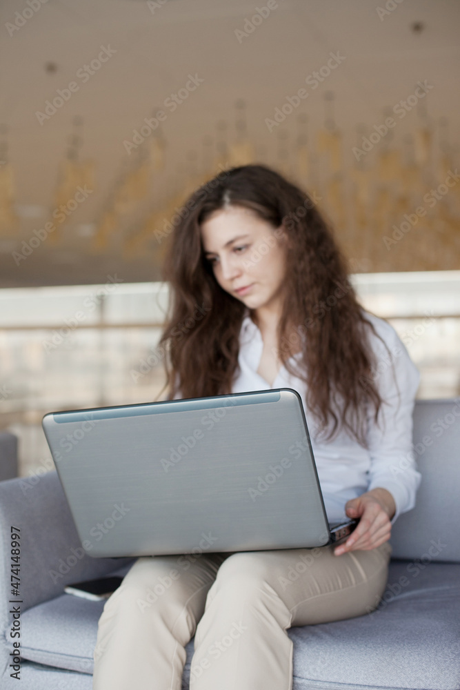 Young woman working on laptop in the public pplace. Caucasian woman with brown hair in the office and using laptop Young woman working on laptop in the public pplace. Caucasian woman with brown hair in the office and using laptop