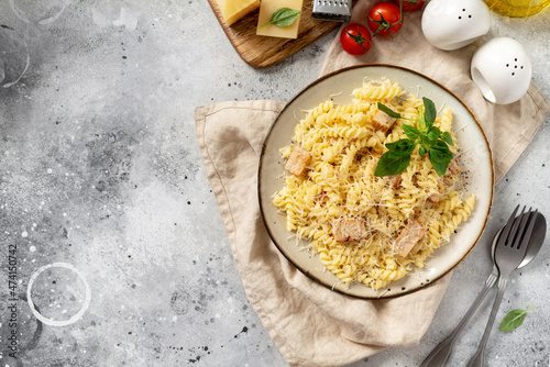 Pasta with ham in cream sauce in a ceramic plate on a light culinary background. Traditional Italian dish girandole in a bowl on the kitchen table top view	 photo