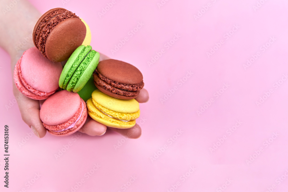 Heap of bright cookies in the hand of a woman on a pink background, copy space. Heap of bright cookies in the hand of a woman on a pink background, copy space.