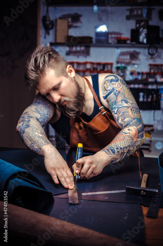 Currier of leather working on a new leather product in the tanner shop photo