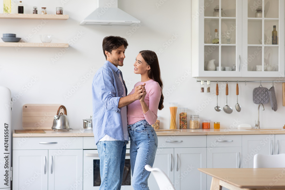 Glad happy attractive young european family couple dancing together, have date in kitchen interior Glad happy attractive young european family couple dancing together, have date in kitchen interior