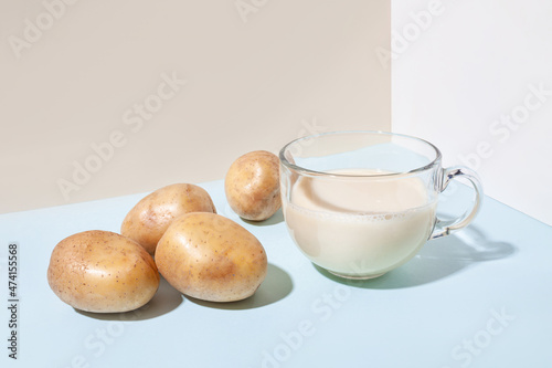 Potato milk. A cup with milk and potato tubers side view. Alternative plant milk