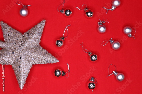 Christmas tree decorations, silver star and small balls on a red background.Top view